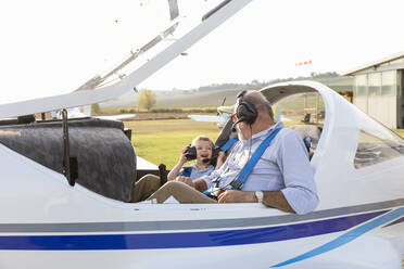 Enkel und Großvater machen sich auf dem Flugplatz an einem sonnigen Tag bereit, ein Flugzeug zu starten - EIF00208