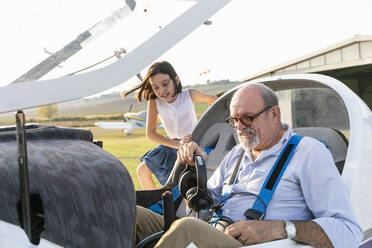 Young girl inside aircraft cockpit with grandfather at airfield - EIF00209