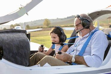 Enkelin sitzt mit Großvater im Flugzeug auf dem Flugplatz - EIF00211