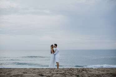 Paar küsst sich, während es am Strand am Meer steht - GMLF00668