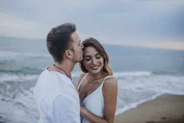 Man kissing woman while standing at beach - GMLF00679