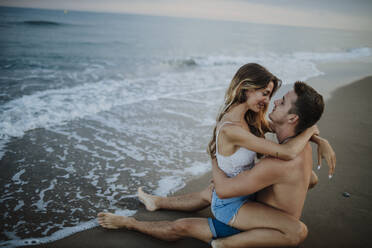 Young couple doing romance while sitting on beach - GMLF00693