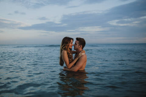 Couple doing romance while standing in water at beach stock photo