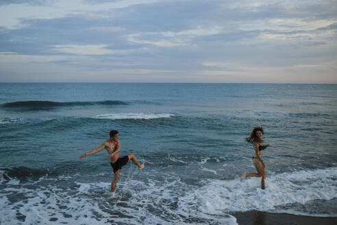 Junges Paar genießt beim Spielen am Strand - GMLF00708