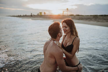 Pärchen in Badekleidung bei einer Romanze im Wasser am Strand - GMLF00714