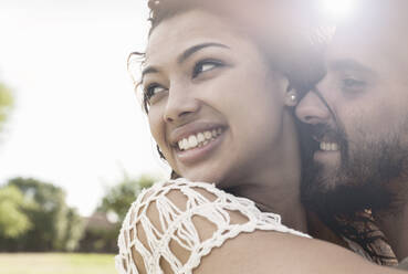 Smiling couple looking while embracing at public park - AJOF00135