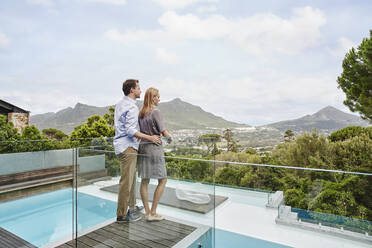 Stehendes Ehepaar mit Blick vom Balkon eines modernen Hauses - RORF02347