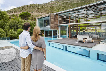 Heterosexual couple looking at modern house while standing outdoors - RORF02356