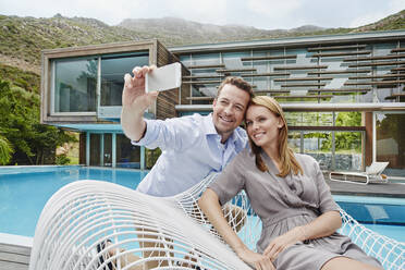 Paar, das ein Selfie mit dem Smartphone macht, während es gegen das Smartphone sitzt - RORF02360