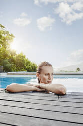 Ernste junge Frau schaut weg, während sie an einem sonnigen Tag im Pool liegt - RORF02406