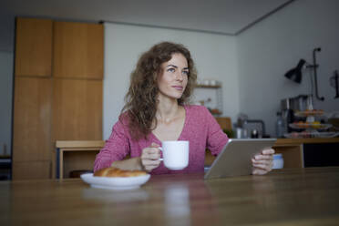 Woman doing breakfast while using digital tablet at home - RBF07970