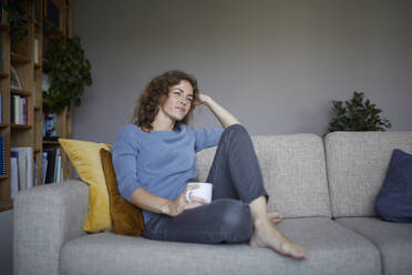 Thoughtful woman with head in hands sitting on sofa at home - RBF07976
