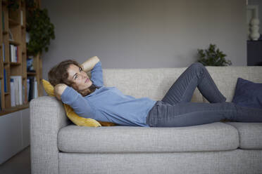 Mid adult woman with head in hands lying on sofa at home - RBF07977