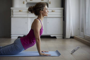 Frau benutzt digitales Tablet während sie zu Hause Yoga macht - RBF07992