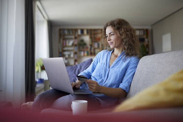 Lächelnde Frau beim Online-Shopping auf dem Laptop zu Hause - RBF07998