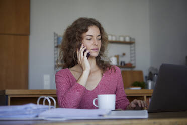 Frau bei der Arbeit, während sie zu Hause am Tisch sitzt - RBF08006