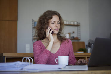 Woman working while sitting by table at home - RBF08006