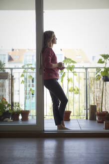 Frau trinkt Kaffee auf dem Balkon zu Hause - RBF08015