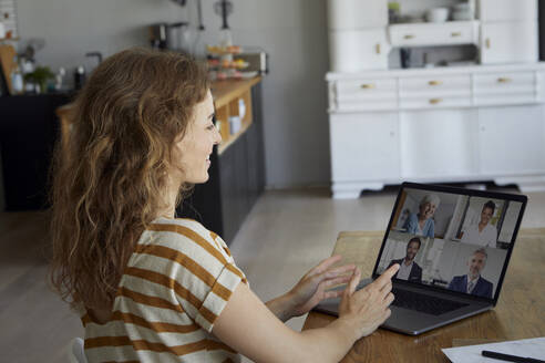 Woman talking on video conference through laptop while sitting at home - RBF08038