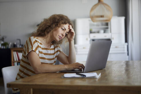 Frustrierte Frau bei der Arbeit am Laptop zu Hause - RBF08041