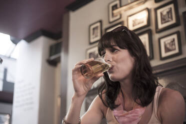 Woman looking away while drinking beer in pub - AJOF00166