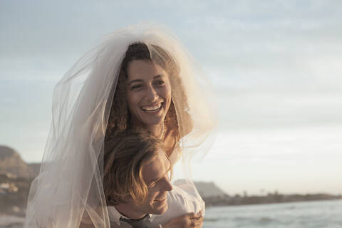 Newlywed couple in wedding dress enjoying at beach during sunset stock photo