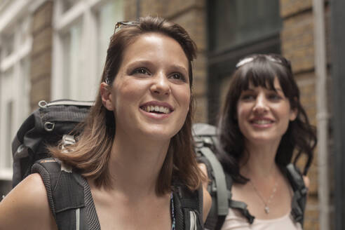 Smiling beautiful backpacker with friend exploring city - AJOF00174