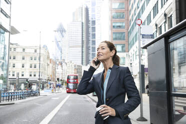 Mature businesswoman talking on mobile phone in city - PMF01286