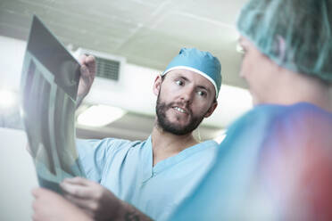 Männliche und weibliche Chirurgen diskutieren über ein Röntgenbild im Krankenhaus - AJOF00194