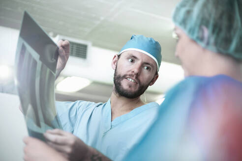 Male and female surgeons discussing over x-ray image in hospital - AJOF00194