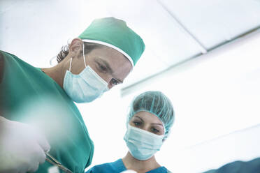 Surgeon performing surgery with nurse in operating room at hospital - AJOF00201