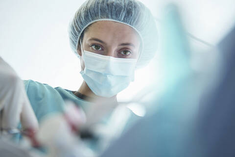 Confident female surgeon operating in intensive care unit at hospital stock photo