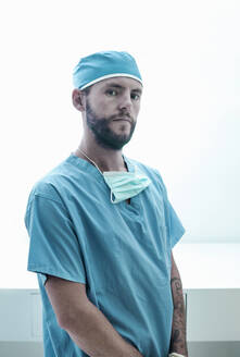 Selbstbewusster männlicher Chirurg vor einem beleuchteten Krankenhaus - AJOF00209