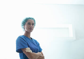 Confident female surgeon standing with arms crossed in intensive care unit at hospital - AJOF00210