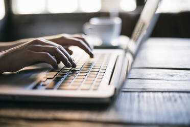 Cropped image of woman hand using laptop in cafe - ABZF03409