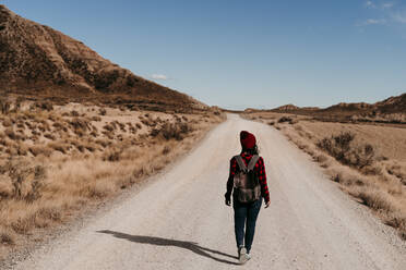 Spain, Navarre, Female tourist walking along empty dirt road in Bardenas Reales - EBBF00860