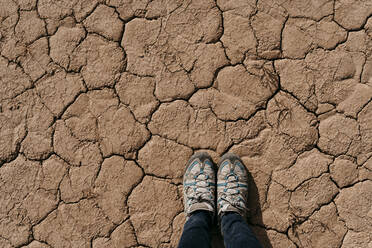 Spanien, Navarra, Schuhe einer Frau, die auf dem trockenen, rissigen Boden von Bardenas Reales steht - EBBF00862