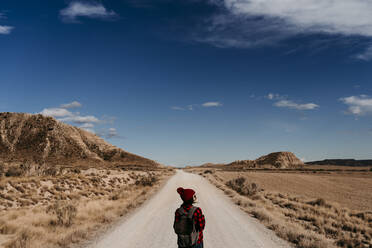Spanien, Navarra, Weibliche Touristin steht in der Mitte eines leeren Feldwegs in Bardenas Reales - EBBF00863