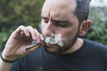 Handsome man smoking marijuana joint outdoors - DSIF00176