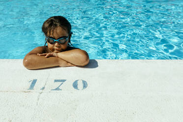 Niedlicher Junge mit verschränkten Armen am Pool lehnend an einem sonnigen Tag - VABF03614