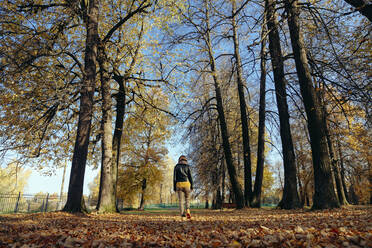 Mittlere erwachsene Frau, die in einem öffentlichen Park an einem sonnigen Tag spazieren geht - KNTF05695