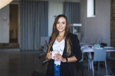 Smiling businesswoman with coffee mug in office - DCRF00923