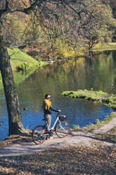 Frau mit Fahrrad im öffentlichen Park an einem sonnigen Tag - KNTF05701