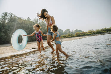 Mother and daughters walking at the river, holding hands - MFF06221