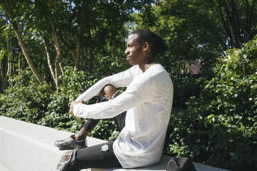 Man sitting on retaining wall at park - VPIF03070