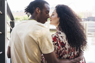 Man and woman rubbing nose while sitting on staircase in city - VPIF03096