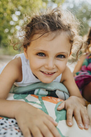 Cute girl lying on front at beach during sunny day stock photo