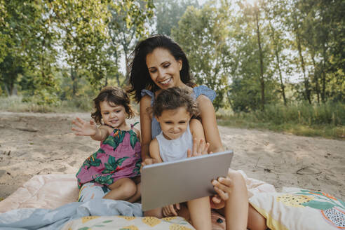 Mutter und Töchter führen einen Videoanruf auf einem digitalen Tablet - MFF06238