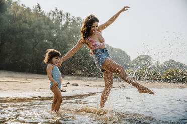 Mother and daughter enjoying in water at beach - MFF06256