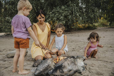 Ältere Frau und Kinder beim Grillen am Strand - MFF06286